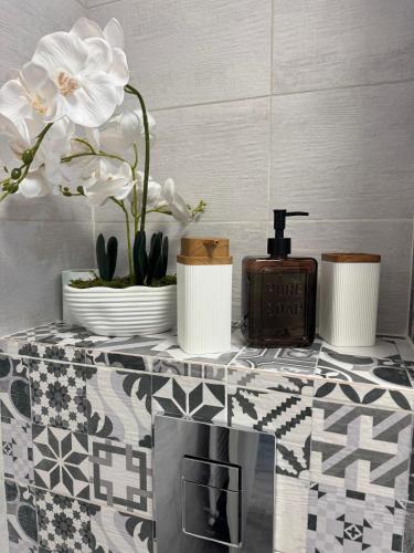 a table with flowers and a soap dispenser on it at Daly Residence in Buzău
