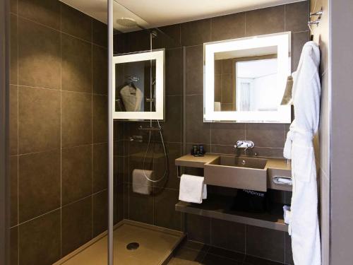 a bathroom with a shower and a sink and a mirror at Novotel Basel City in Basel