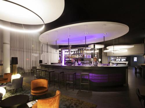 a bar in a room with chairs and tables at Novotel Basel City in Basel