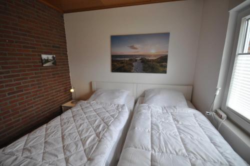two beds in a room with a brick wall at Nr 31 - Ferienhaus Am Yachthafen in Carolinensiel