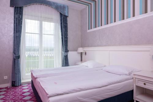 a bedroom with a large bed and a window at Pałac Domaniowski in Wieniawa