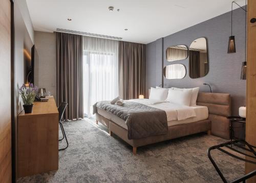 a bedroom with a large bed and a mirror at Hotel Experience in Bečej