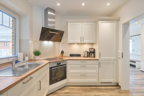 a kitchen with white cabinets and a sink at Kanalkajüte Wilhelm in Hanerau-Hademarschen