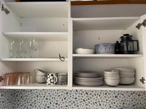 a white cabinet filled with plates and bowls at Sleepy Hollow adorable peaceful guesthouse. in Gnarabup