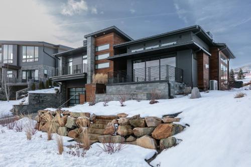 a house in the snow with a rock wall at 1506 W Orion Way - SkyRidge 6 BR Home with Hot Tub home in Keetley
