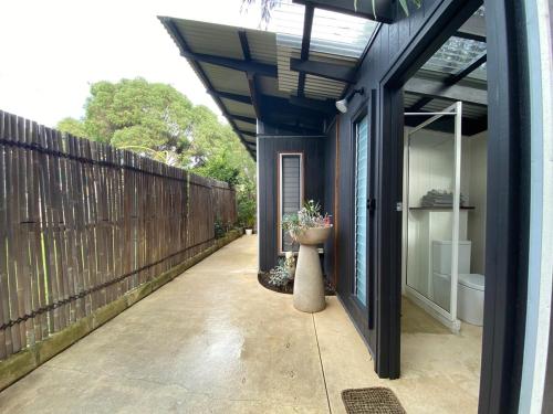 a patio with a wooden fence and a vase with flowers at Sleepy Hollow adorable peaceful guesthouse. in Gnarabup