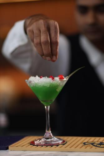 a person serving a green drink in a martini glass at Ramada Encore by Wyndham Siliguri Sevoke Road in Siliguri