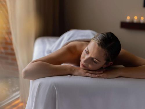 a woman laying on a bed with her head on herarms at Pullman Auckland Hotel & Apartments in Auckland
