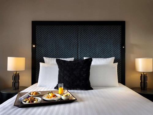 a tray of food on a bed with two lamps at Pullman Auckland Hotel & Apartments in Auckland