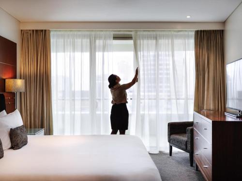 a woman standing in a hotel room looking out the window at Pullman Auckland Hotel & Apartments in Auckland