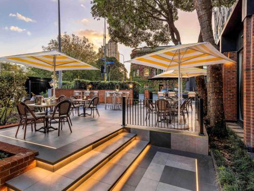 a patio with tables and chairs and umbrellas at Pullman Auckland Hotel & Apartments in Auckland