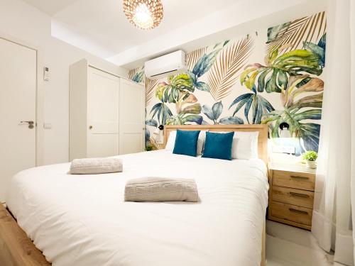 a bedroom with a large white bed with blue pillows at Oasis Beach Home Meloneras with jacuzzi in Maspalomas