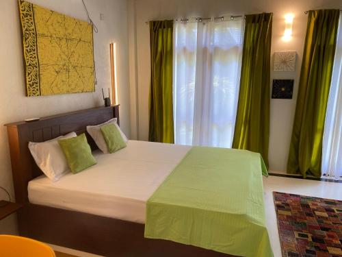 a bedroom with a large bed with green curtains at New Palms Villa Induruwa Homestay in Induruwa