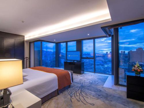 a bedroom with a large bed and a large window at Pullman Guiyang in Guiyang