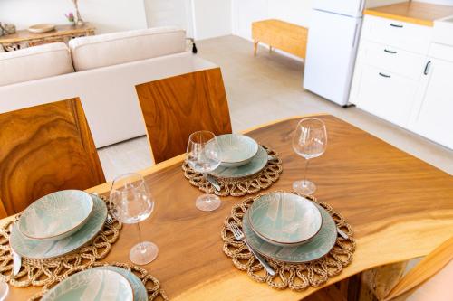 a wooden table with plates and wine glasses on it at 2BR Emerald Villa Private Pool & Sea View B30-1 in Amphoe Koh Samui