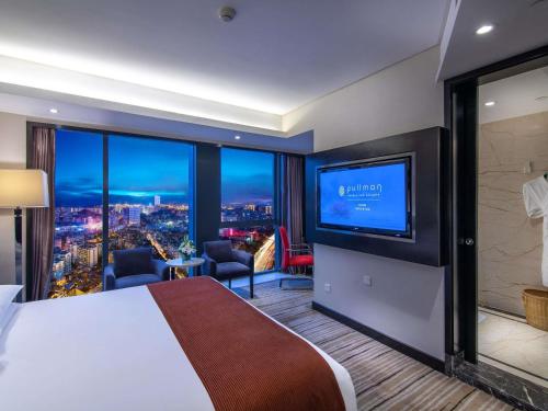 a hotel room with a large bed and a flat screen tv at Pullman Guiyang in Guiyang