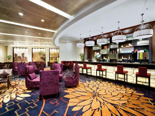 a lobby with a bar and some purple chairs at Pullman Guiyang in Guiyang