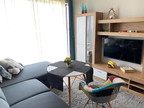 a living room with a couch and a table and a tv at D&N Apartments Синеморец in Sinemorets