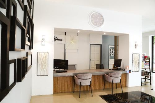 a lobby with a bar with stools and a clock on the wall at Di Yana Patong in Patong Beach
