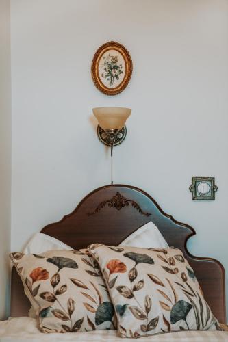 a bed with two pillows and a clock on the wall at Villa Serena in Siklós