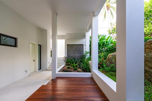 an open hallway with white walls and wood floors at Anzhu Seamate Villa Samui in Amphoe Koh Samui