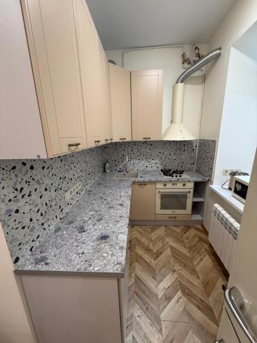 a kitchen with white cabinets and marble counter tops at Borytchyw in Kyiv