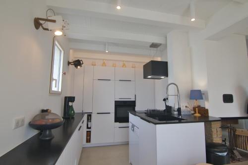 a kitchen with white cabinets and a black counter top at Rénovation d'Architecte- Mer &Phare à pied in Saint-Clément-des-Baleines