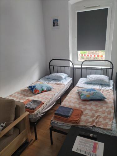 two twin beds in a room with a window at Stargard centrum Apartamenty Zajazd in Stargard