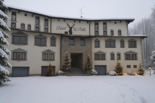 リオルナートにあるHotel Le Polleの雪中のクリスマスの木が植えられた大きな建物