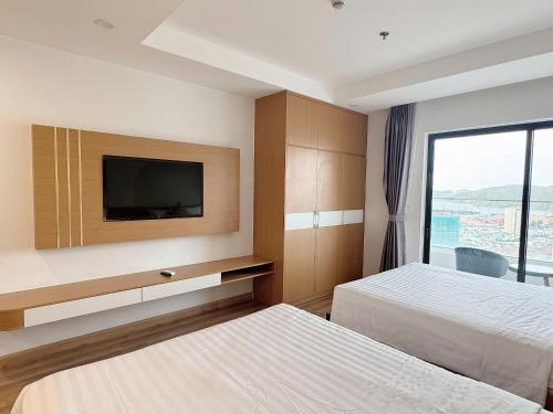 a hotel room with two beds and a flat screen tv at Seafront Apartment TMS Quy Nhơn in Quy Nhon