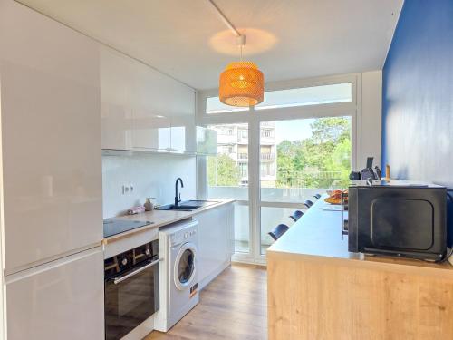 Il comprend une cuisine avec un évier et une télévision sur un comptoir. dans l'établissement Le Lagon, Moderne, Parking & Proche du Centre, à Saint-Brieuc