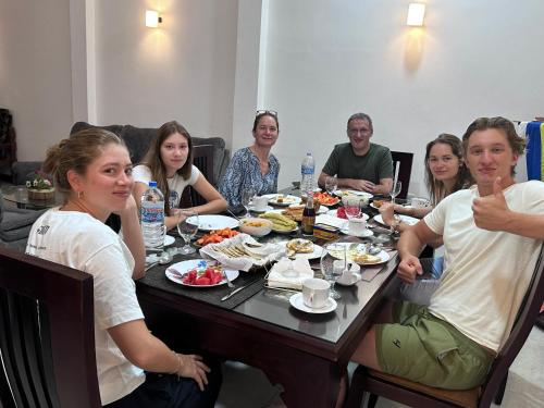 a group of people sitting around a table eating food at Emerald Home Stay in Anuradhapura