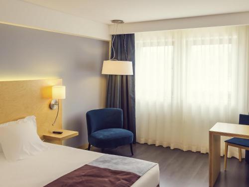 a hotel room with a bed and a chair and a window at Hotel Mercure Braga Centro in Braga