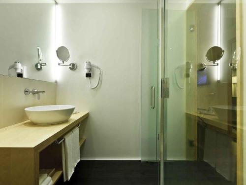 a bathroom with a sink and a glass shower at Hotel Mercure Braga Centro in Braga