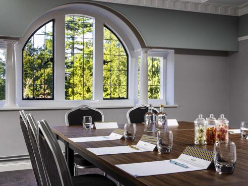 a conference room with a wooden table and windows at Mercure Tunbridge Wells Hotel in Royal Tunbridge Wells