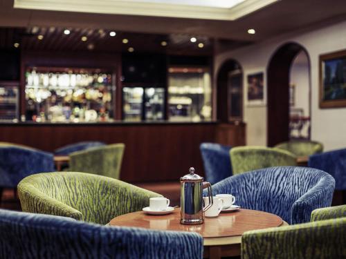 a restaurant with a table and chairs with a kettle on it at Mercure Norwich Hotel in Norwich