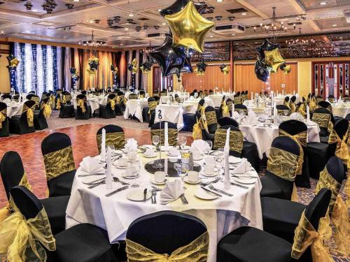 a banquet hall with white tables and black chairs at Mercure Norwich Hotel in Norwich