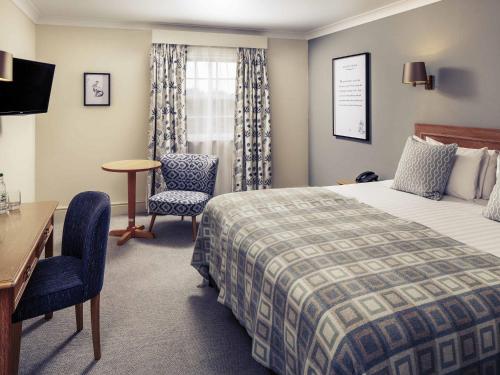 a hotel room with a bed and a desk and chair at Mercure Gloucester Bowden Hall Hotel in Gloucester