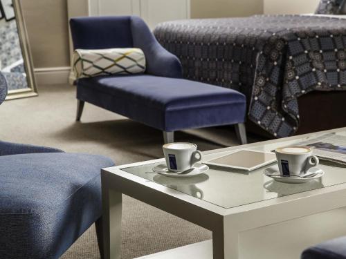 a living room with two coffee cups on a table at Mercure Gloucester Bowden Hall Hotel in Gloucester