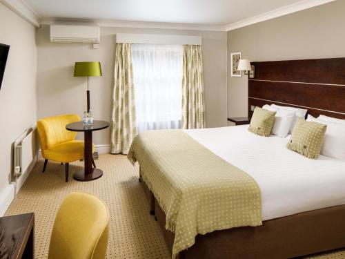 a hotel room with a bed and a table and chair at Mercure Gloucester Bowden Hall Hotel in Gloucester