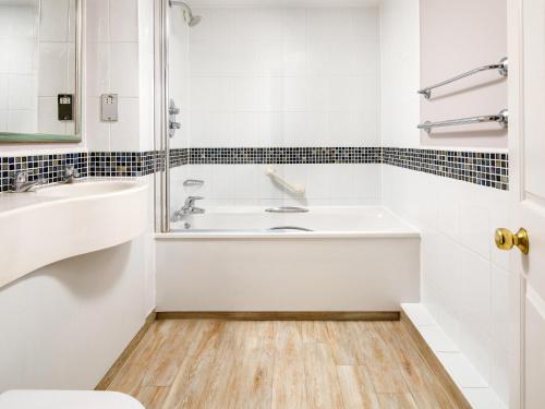 a white bathroom with a tub and a sink at Mercure Gloucester Bowden Hall Hotel in Gloucester