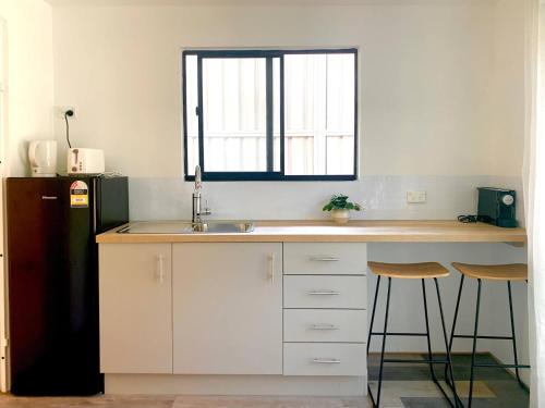 a kitchen with a counter with a sink and a refrigerator at Garden Apartment in the heart of Bondi in Sydney