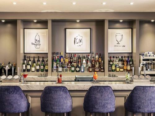 a bar with purple bar stools and bottles of alcohol at Mercure Gloucester Bowden Hall Hotel in Gloucester