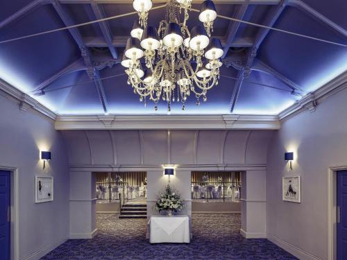 a large lobby with a blue ceiling and a chandelier at Mercure Gloucester Bowden Hall Hotel in Gloucester