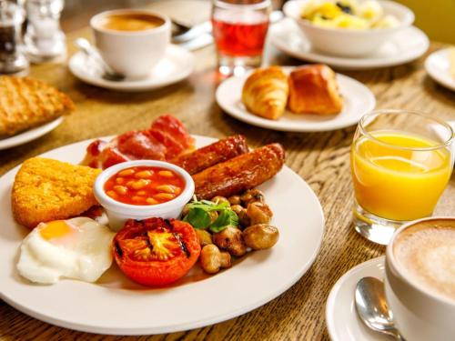 a table with a plate of breakfast foods and coffee at Mercure Bristol North The Grange Hotel in Bristol
