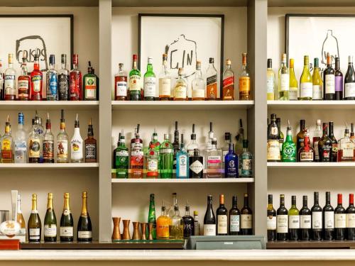 a shelf filled with lots of bottles of alcohol at Mercure Bristol North The Grange Hotel in Bristol