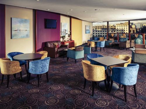 a hotel lobby with tables and chairs and a couch at Mercure Manchester Piccadilly Hotel in Manchester
