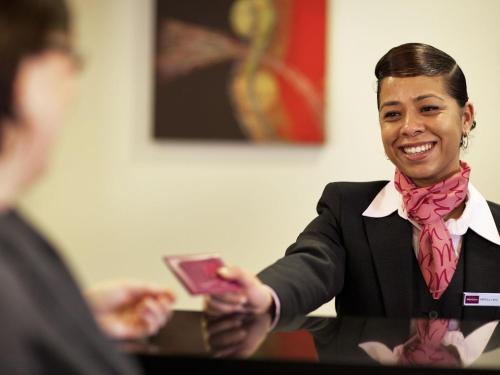 a woman wearing a bow tie holding a cell phone at Mercure Manchester Piccadilly Hotel in Manchester