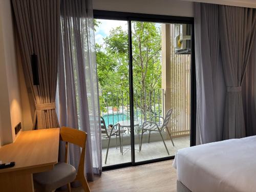 a bedroom with a bed and a balcony with a table and chairs at PAAK Hotel Suvarnabhumi in Lat Krabang