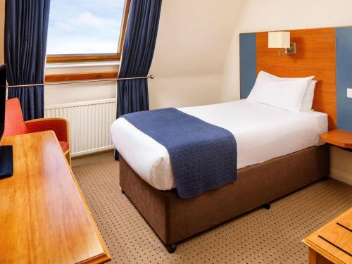 a hotel room with a bed and a desk and a chair at Mercure Bolton Georgian House Hotel in Bolton